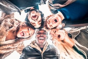 Multi-ethnic group of friends in circle - Several people of diverse ethnics smiling and looking down at camera - Concepts about friendship, teamwork, immigration and unity